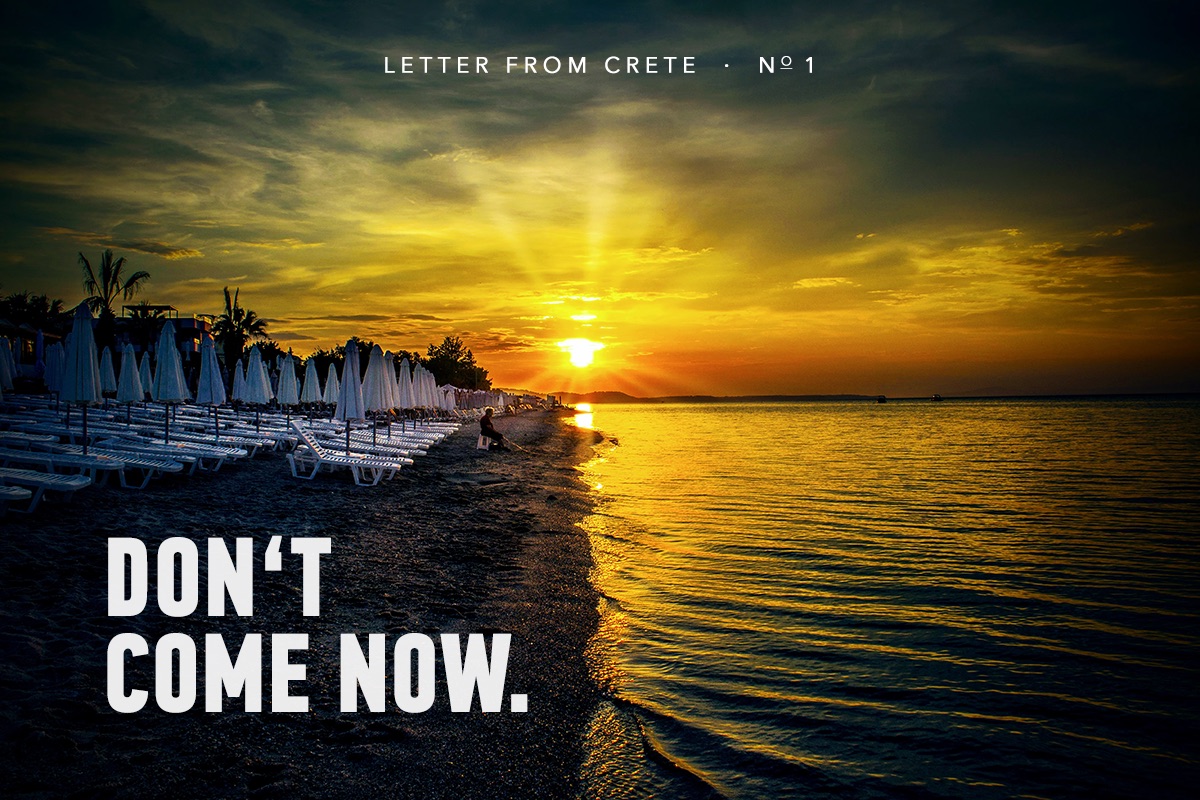 Rows of empty sun loungers along a Crete beach at sunset, the sea burning gold—Don’t come now.